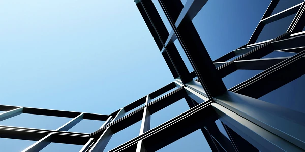 Ein Blick auf die Architektur eines modernen Gebäudes mit schrägen Glasflächen und einem klaren blauen Himmel im Hintergrund.