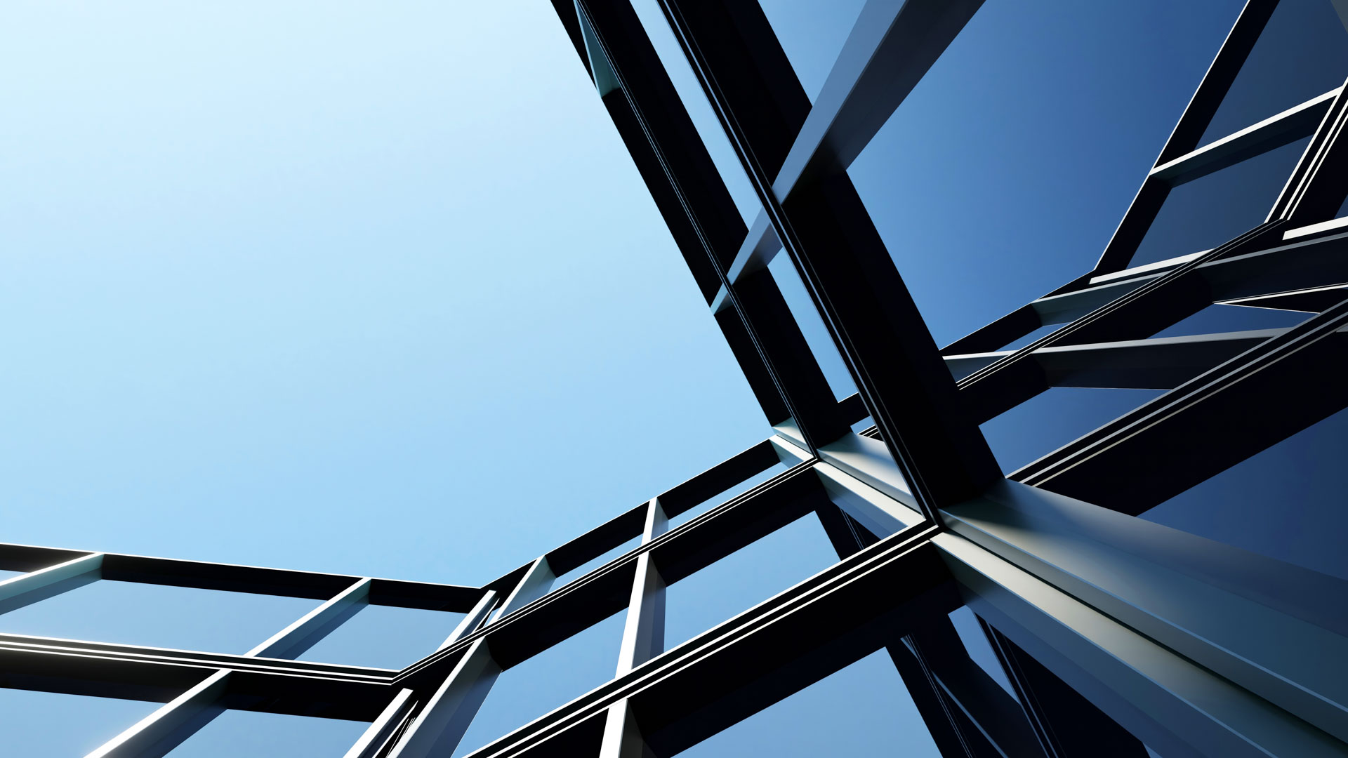 Ein Blick auf die Architektur eines modernen Gebäudes mit schrägen Glasflächen und einem klaren blauen Himmel im Hintergrund.